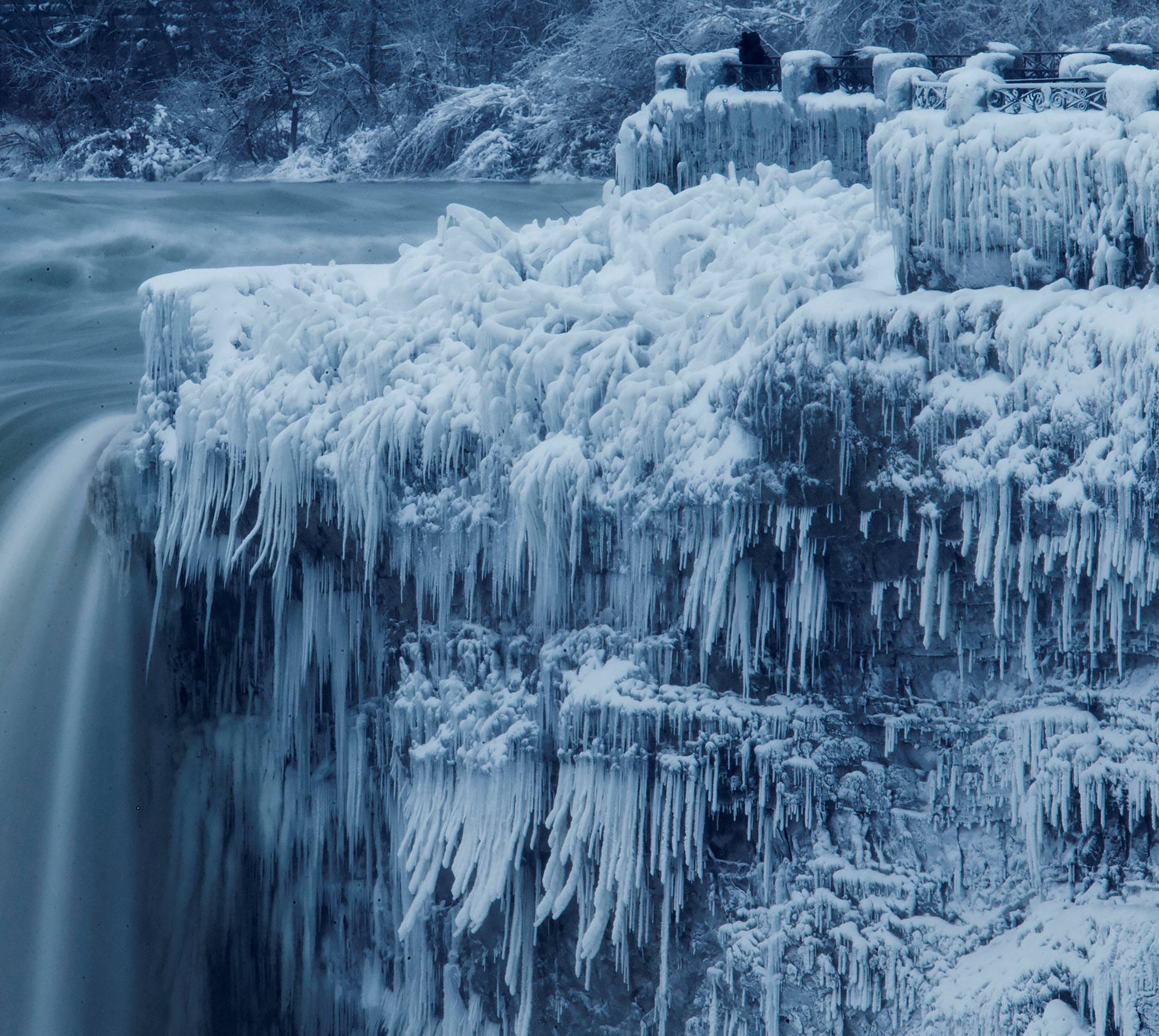 A lone visitor takes a picture near the brink of the ice covered Horseshoe Falls in Niagara Falls