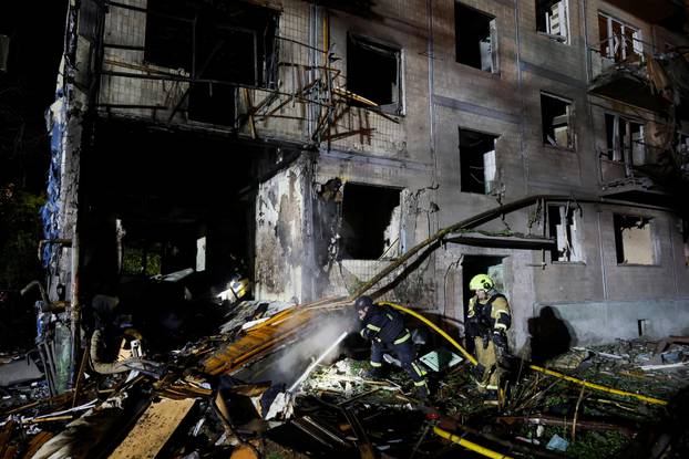 Firefighters work at the site of an apartment building hit by a Russian missile strike in Kyiv