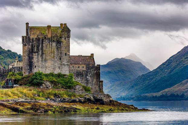 Dramatic Scottish castle with a moody sky on the shore of a sea 