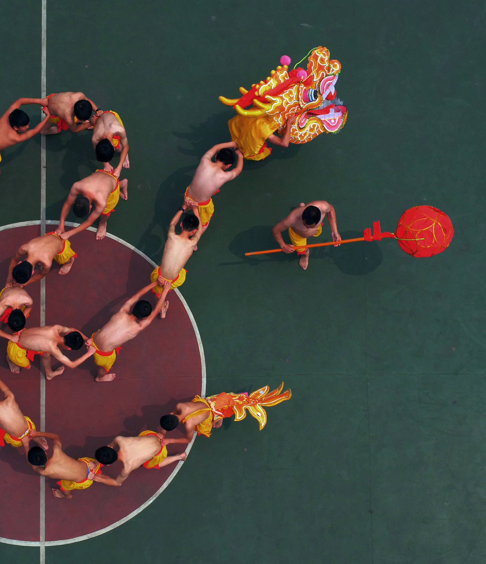 Students learn to perform a dragon dance under the instruction of a local artist at a playground in Chongqing