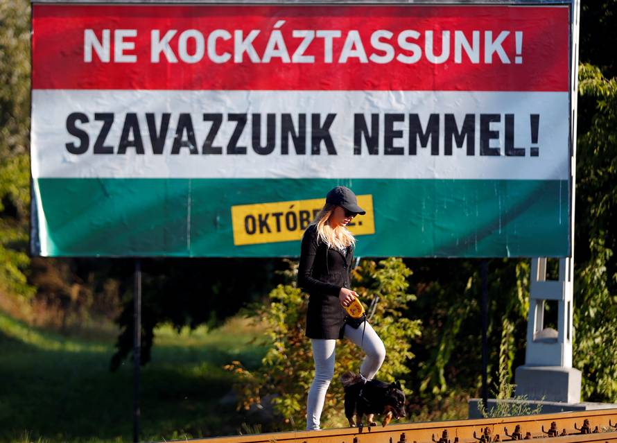 Woman walks with her dog in front of the Hungarian goverment's referendum poster regarding EU migrant quotas in Budapest