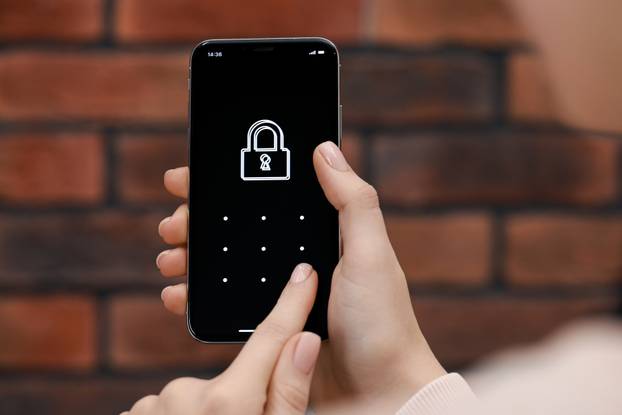 Woman unlocking smartphone with blocked screen indoors, closeup