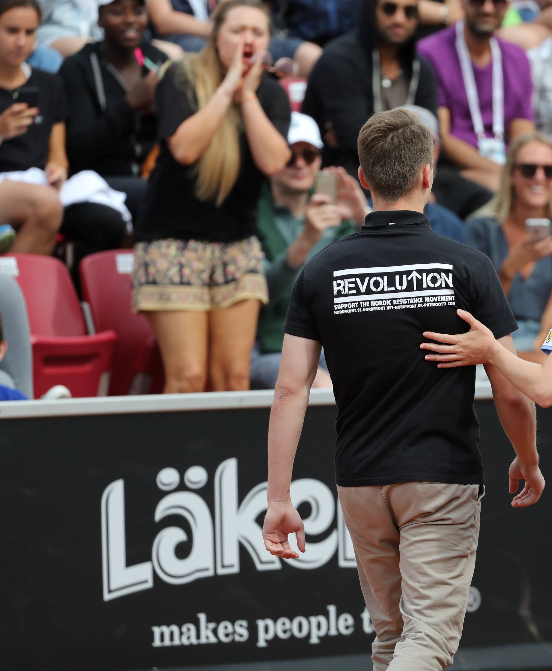 A man is escorted out of the court after raising his right fist during the ATP tennis tournament Swedish Open semi-final match between Fernando Verdasco of Spain and David Ferrer of Spain, in Bastad