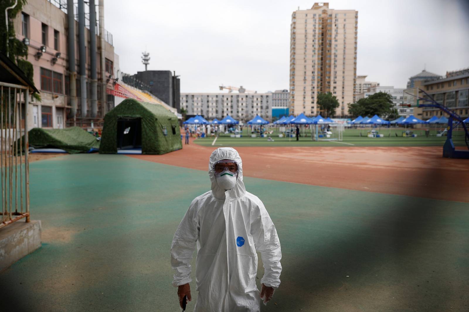 Security staff in a personal protection suit approaches the photographer at a testing site at the Guangan Sport Center after an unexpected spike of cases of the coronavirus disease (COVID-19) in Beijing