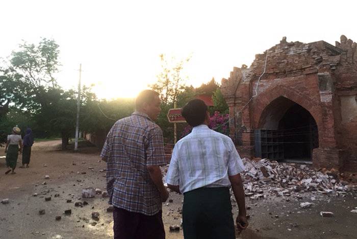 Two men look at a collapsed entrance of a pagoda after an earthquake in Bagan