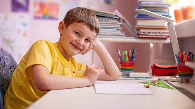 Happy,Schoolboy,Doing,Homework,With,Training,Books,And,Notebooks,At