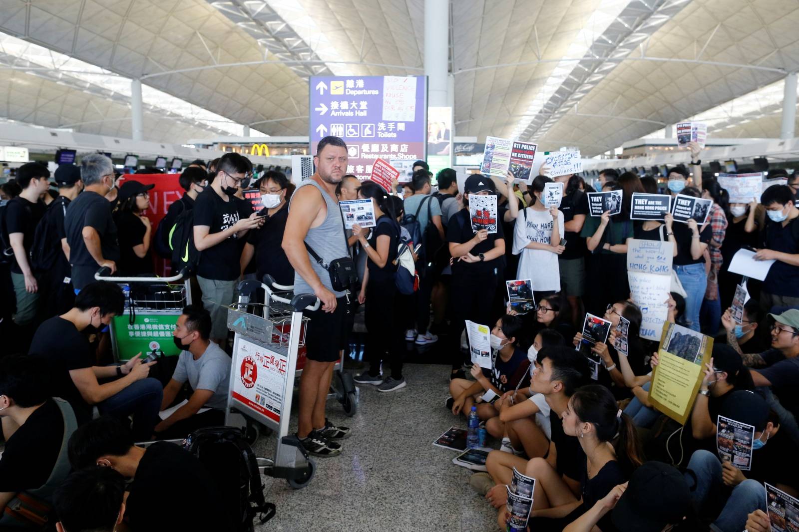 A passenger waits at the departure hall as anti-extradition bill protesters rally at of Hong Kong airport in Hong Kong