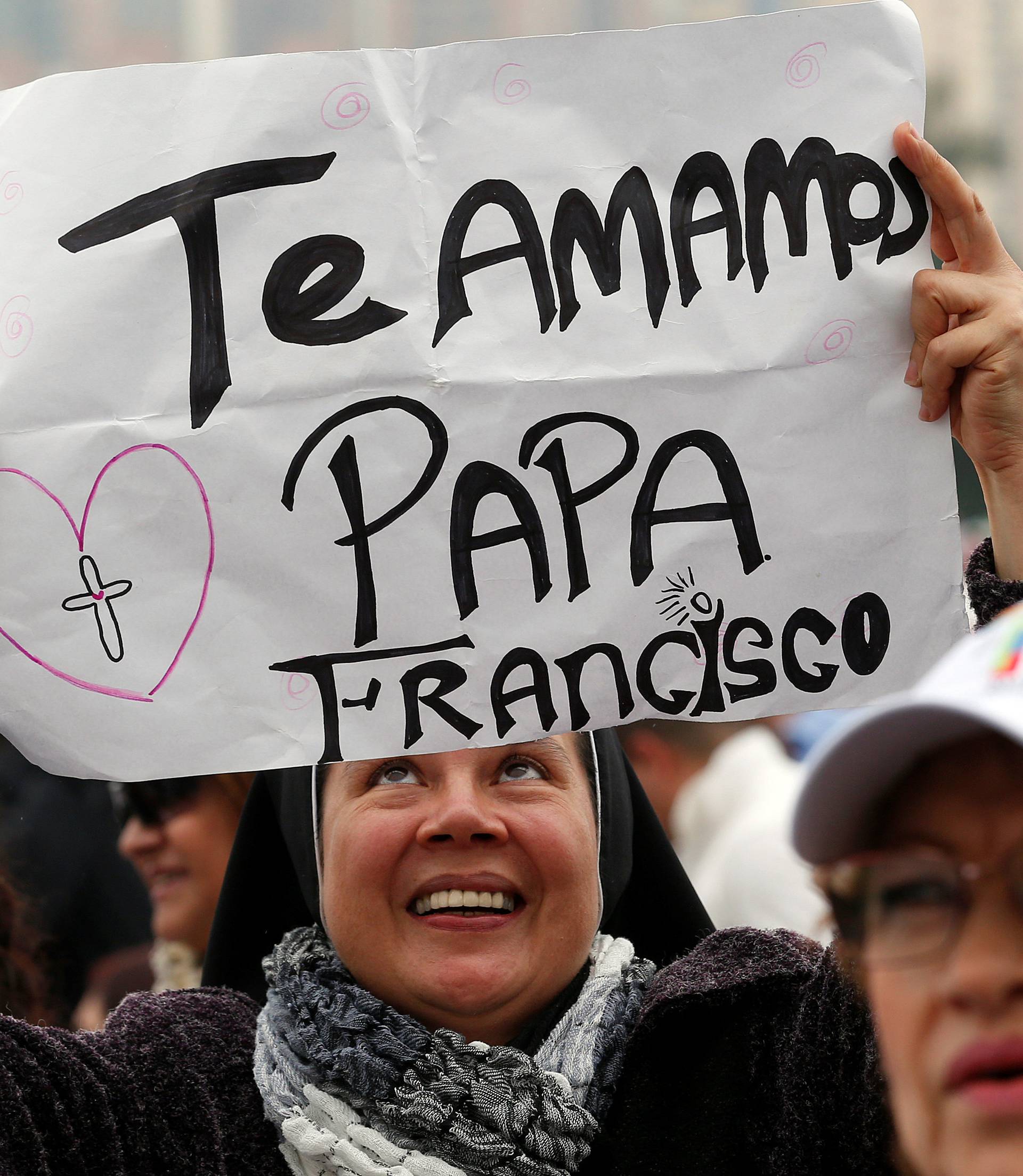 Faithful holds a placard "We love you Pope" before Pope Francis arrives to leads a holy mass at Enrique Olaya Herrera airport in Medellin