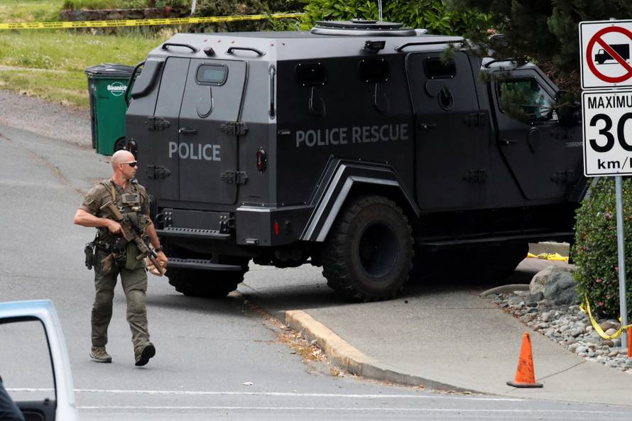 A police officer looks on after two armed men entering a bank were killed in a shootout with the police in Saanich