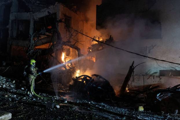An Israeli firefighter works to put out a fire on a car at the site of a projectile impact, in Tel Aviv
