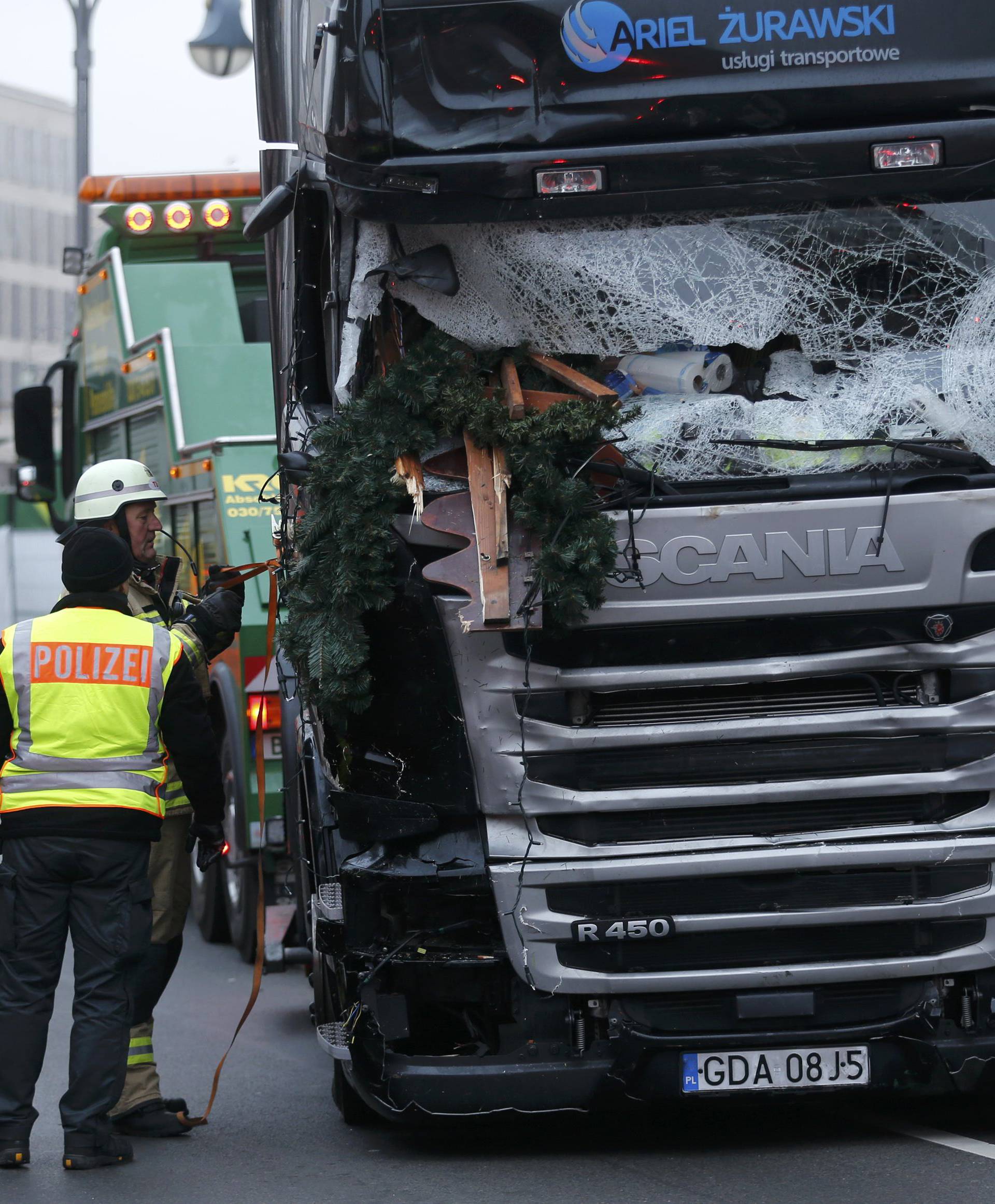 Fire fighters stand beside the truck which ploughed last night into a crowded Christmas market in the German capital Berlin