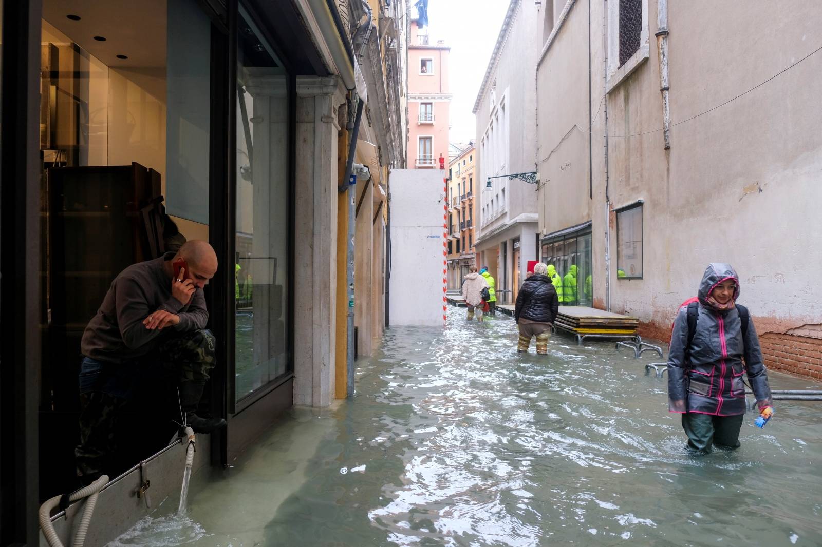 People walk in the flooded street during a period of seasonal high water in Venice