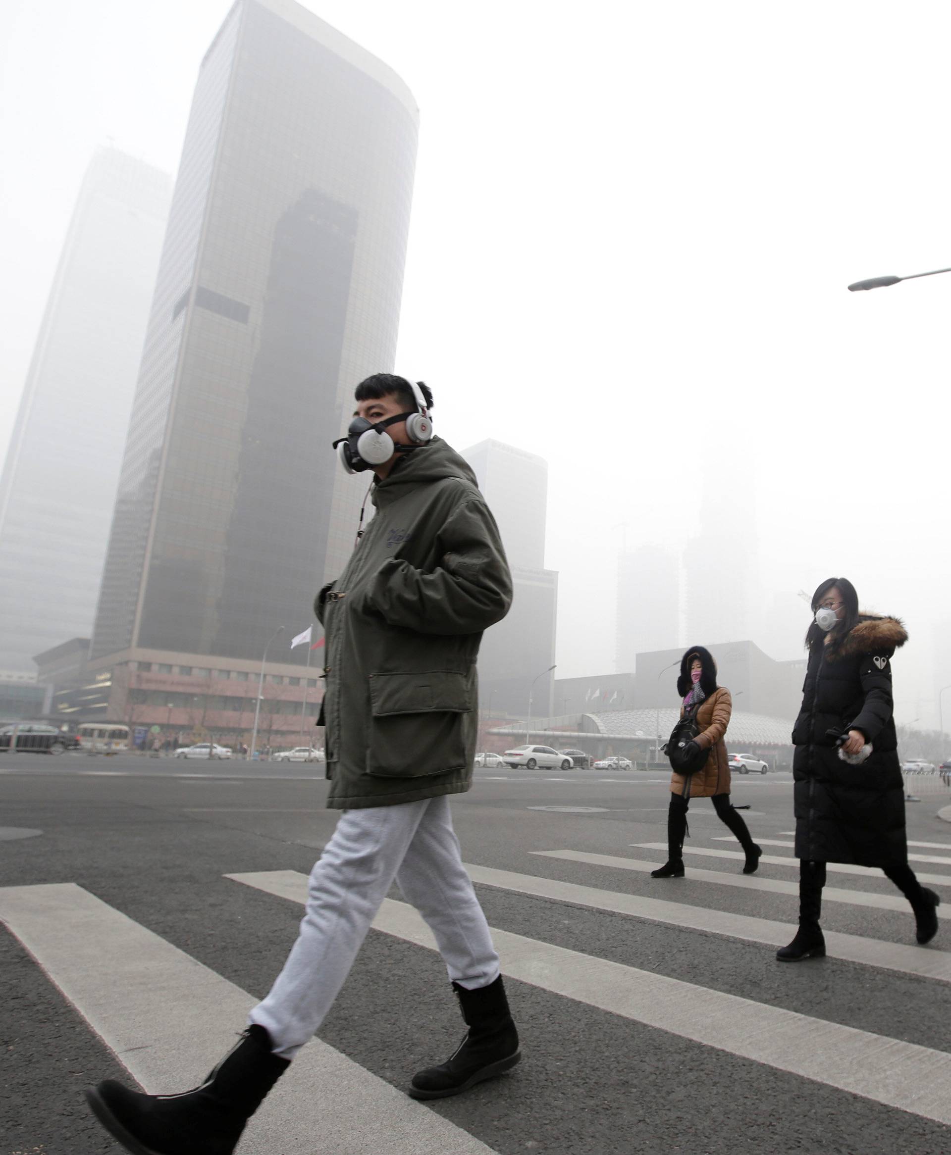 A man wearing a respiratory protection mask walks toward an office building during smog in Beijing