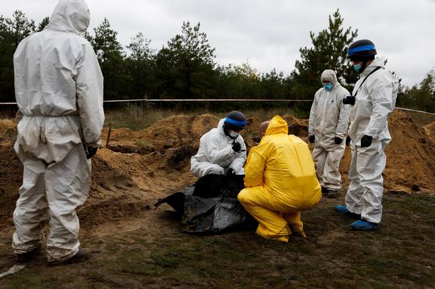 A forensics films a body they exhumed from, what Ukrainians said, a mass grave, in the newly recaptured town of Lyman,