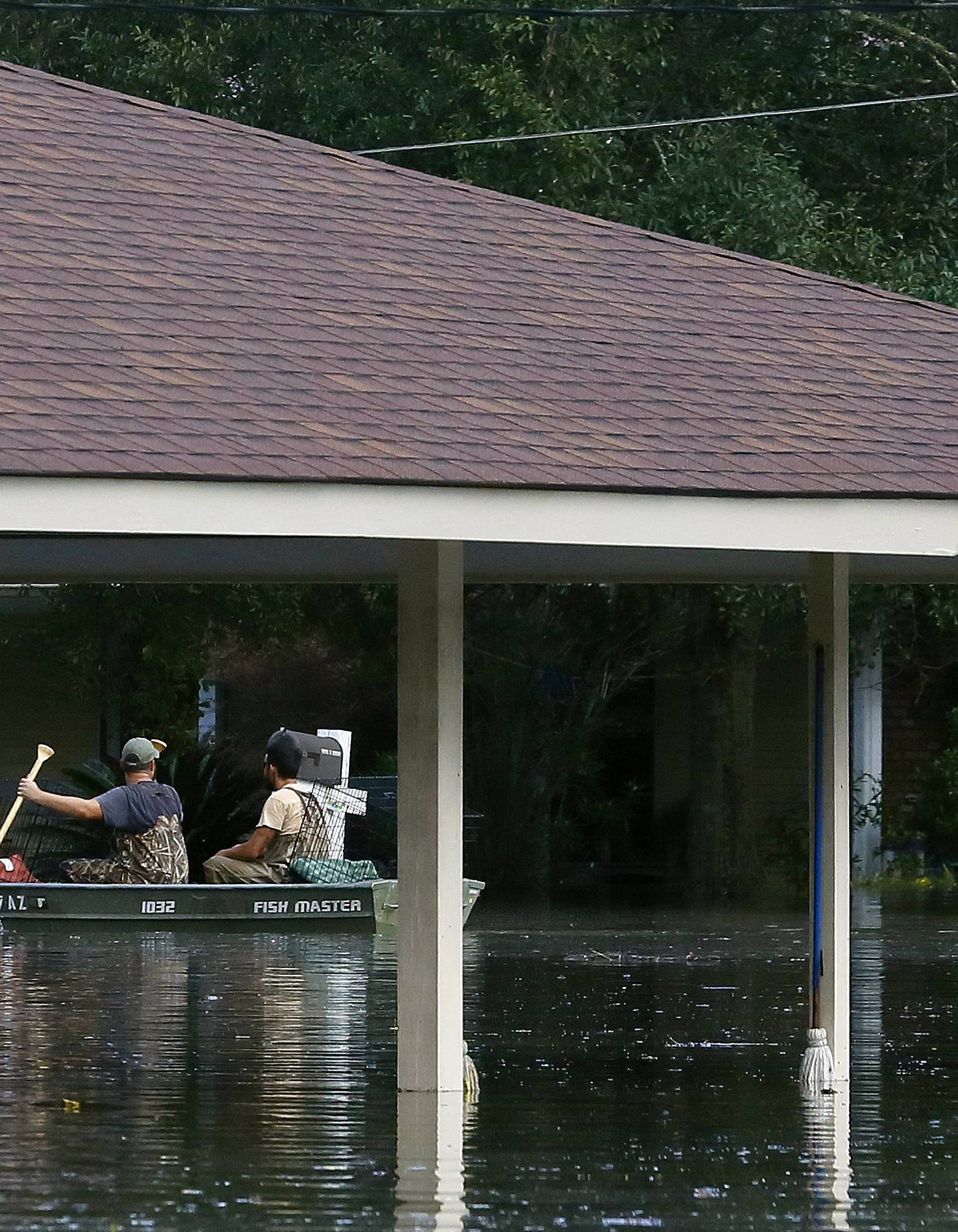 Residents use a boat to navigate through flood waters in Ascension Parish