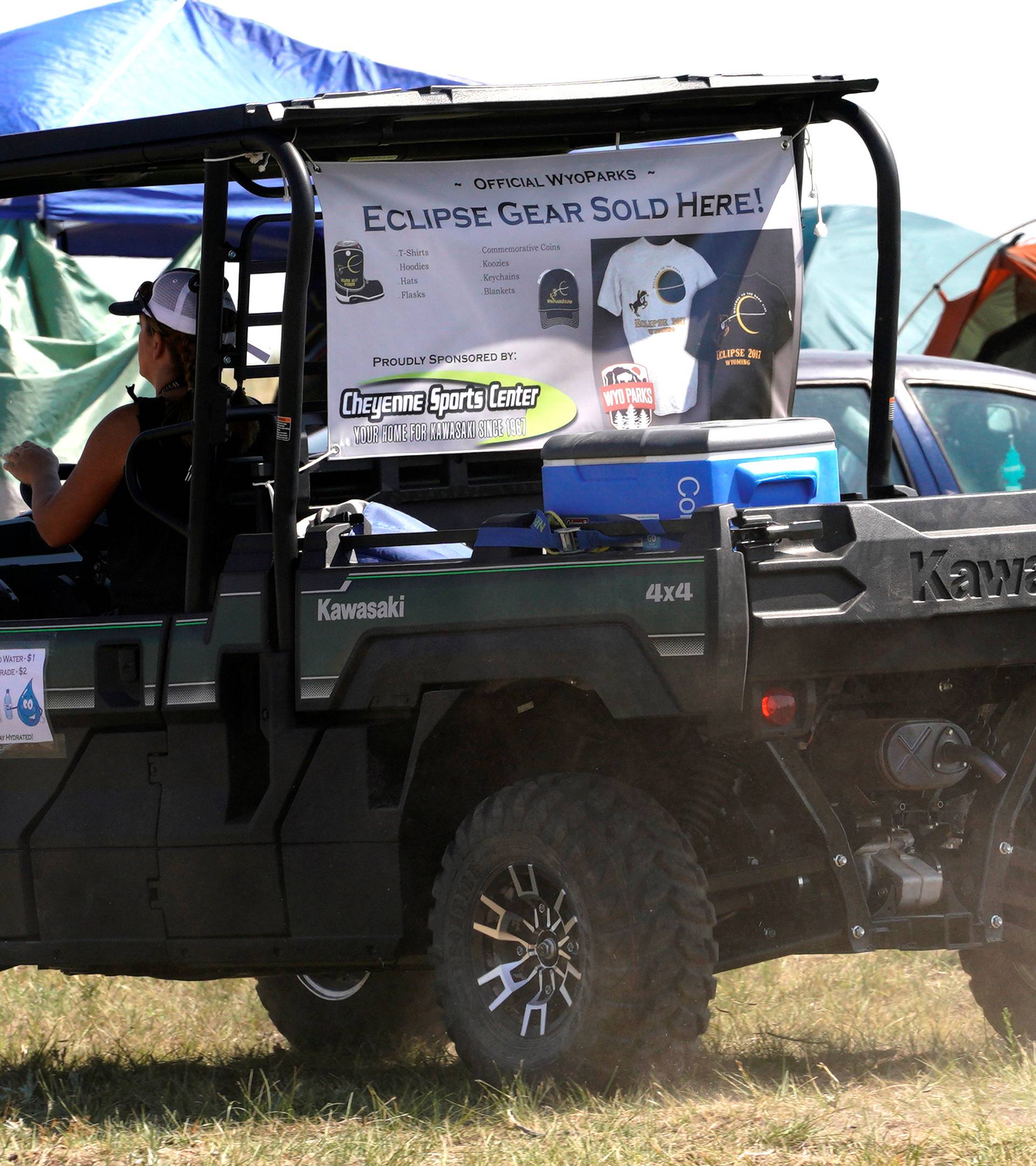 A mobile souvenir seller of eclipse merchandise rides through a campground near Guernsey