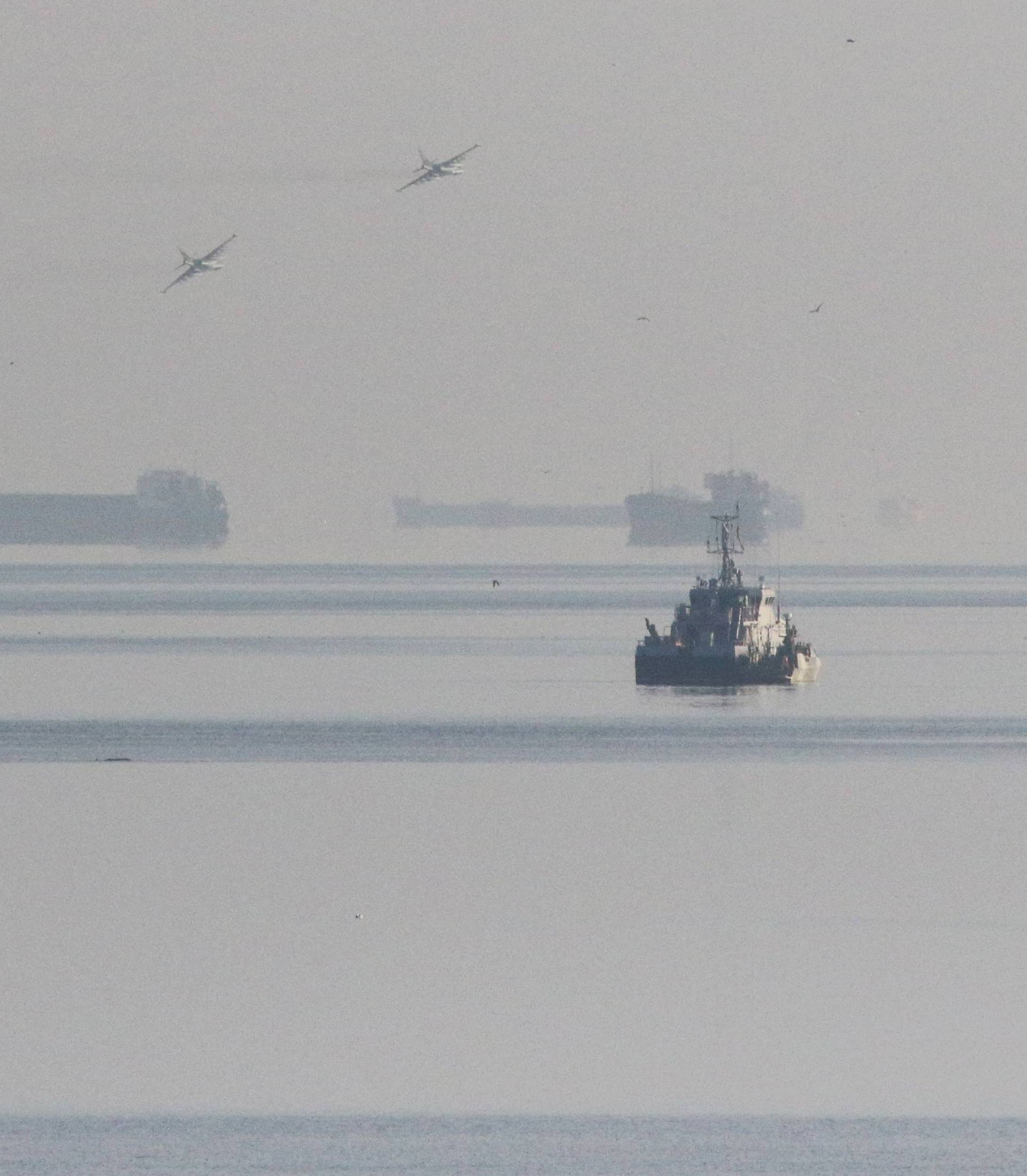 Russian jet fighters fly over vessels after the channel beneath a bridge connecting the Russian mainland with the Crimean Peninsula was blocked to stop three Ukrainian navy ships from entering the Sea of Azov via the Kerch Strait in the Black Sea