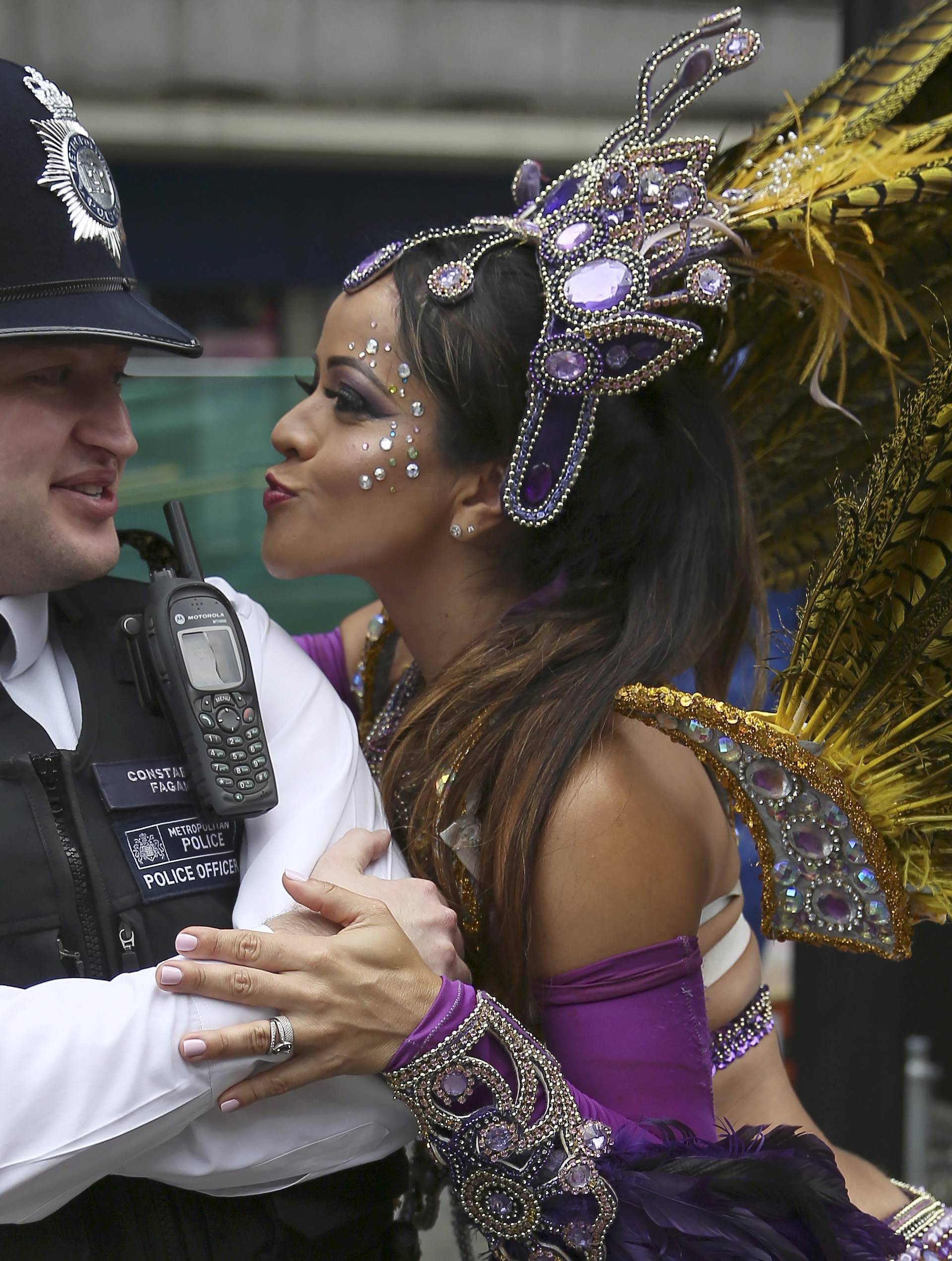 A performer dances with police during the Notting Hill Carnival in London