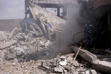 Syrian firefighters are seen inside the destroyed Scientific Research Centre in Damascus