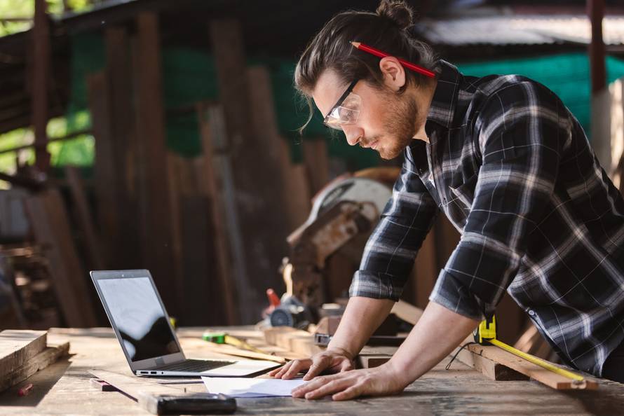 Young,Carpenter,Caucasian,Man,With,Laptop,And,Looking,Paper,Work