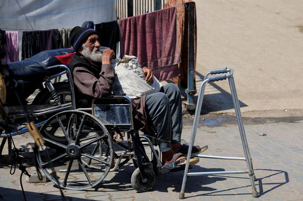 A displaced Palestinian man sits in his wheelchair in front of his tent inside an UNRWA school where he has taken refuge after being displaced, in Khan Younis, southern Gaza Strip