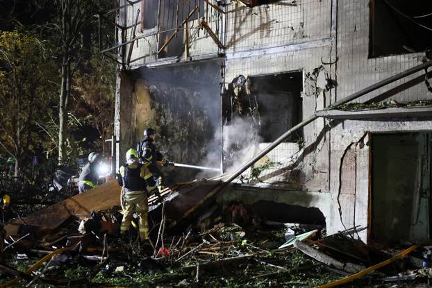 Firefighters work at the site of an apartment building hit by a Russian missile strike in Kyiv