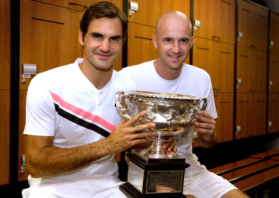 Roger Federer of Switzerland and his coach Ivan Ljubicic pose with the trophy after Federer won the Australian Open tennis tournament men's singles final, in the locker room in Melbourne