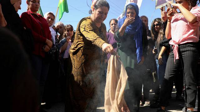 Women burn headscarves during a protest over the death of Mahsa Amini in Iran, in the Kurdish-controlled city of Qamishli