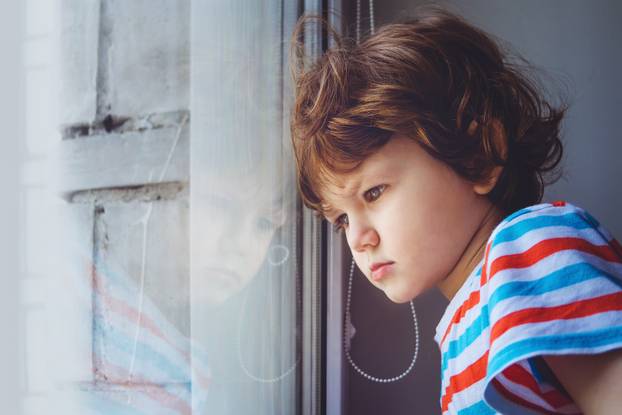 Little child looking out the window through the blinds. Backgrou