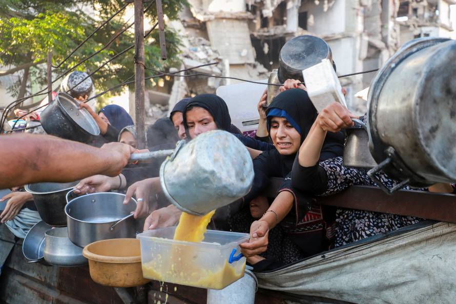Palestinians gather to receive food from a charity kitchen amid hunger crisis, in Gaza City