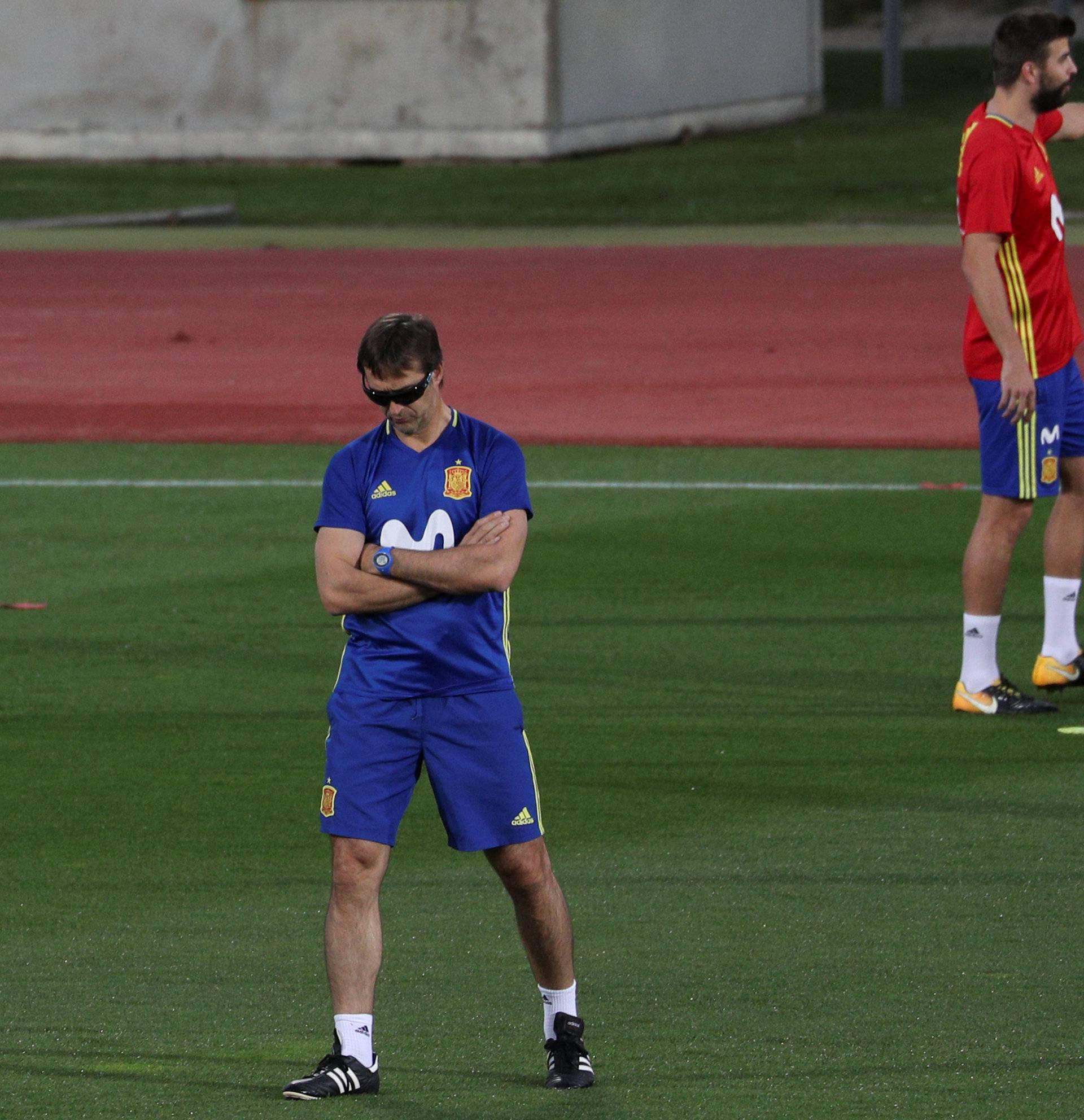 Spain's head coach Lopetegui walks past player Pique during a training session in Las Rozas