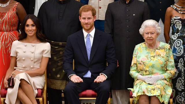 FILE PHOTO: Britain's Queen Elizabeth, Prince Harry and Meghan, the Duchess of Sussex pose for a picture with some of Queen's Young Leaders at a Buckingham Palace reception following the final Queen's Young Leaders Awards Ceremony, in London