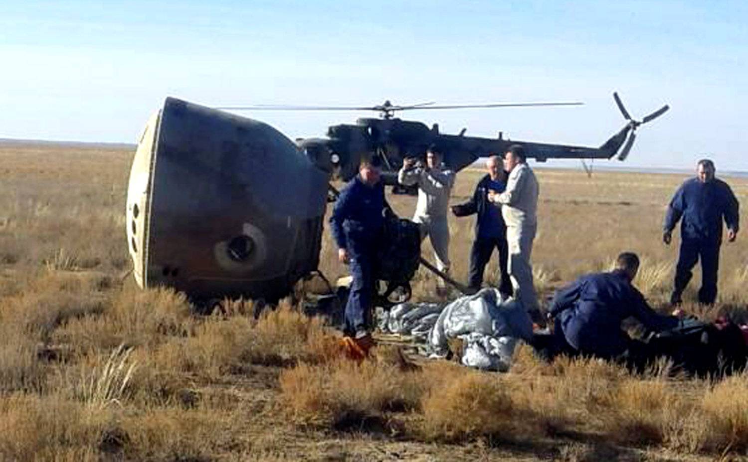 Specialists gather near the Soyuz capsule transporting U.S. astronaut Hague and Russian cosmonaut Ovchinin after it made an emergency landing near Zhezkazgan