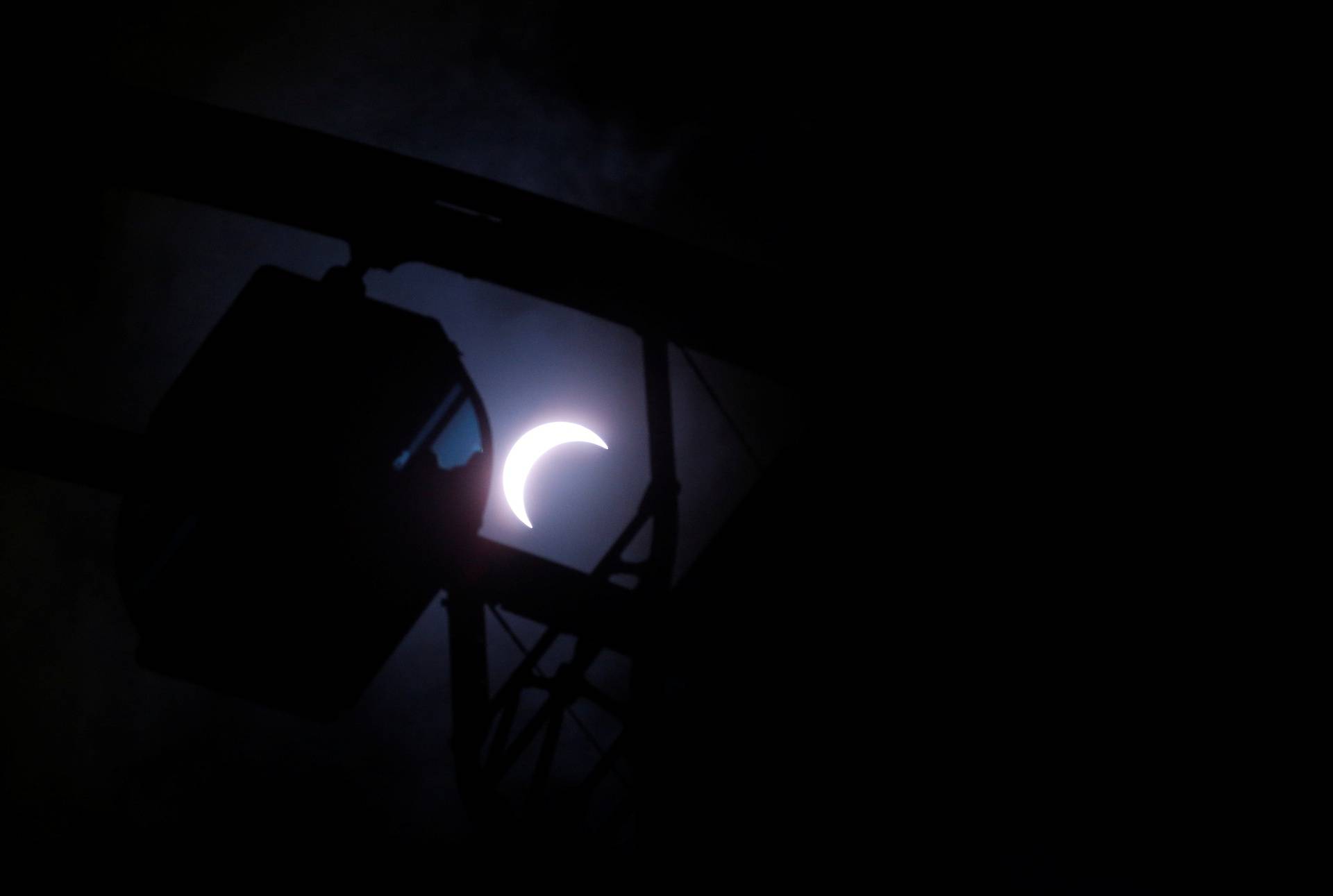 A partial solar eclipse is seen over a ferris wheel, in Hong Kong