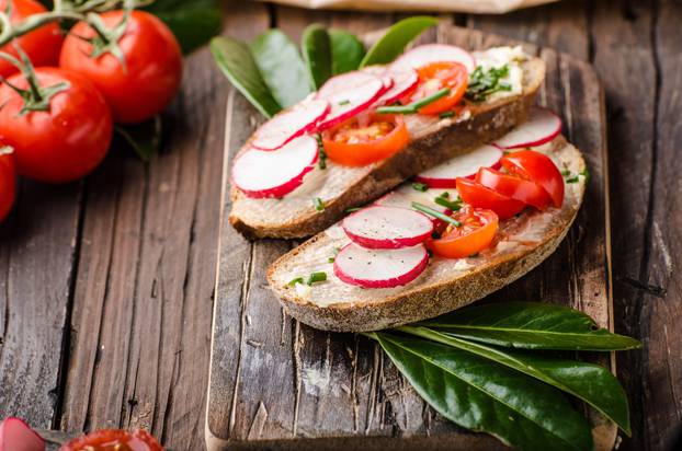 Homemade bread with fresh creame, herbs and radishes