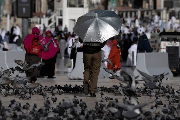 A policeman walks with an umbrella to escape from extreme weather at the grand mosque during the annual hajj pilgrimage in the holy city of Mecca