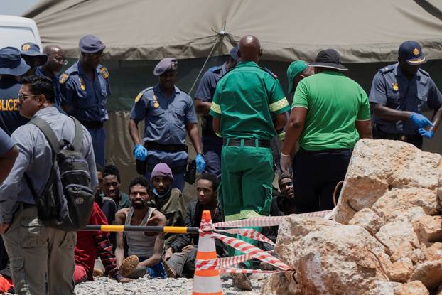 Rescued miners are seen as they are processed by police after being rescued at the mine shaft, in Stilfontein