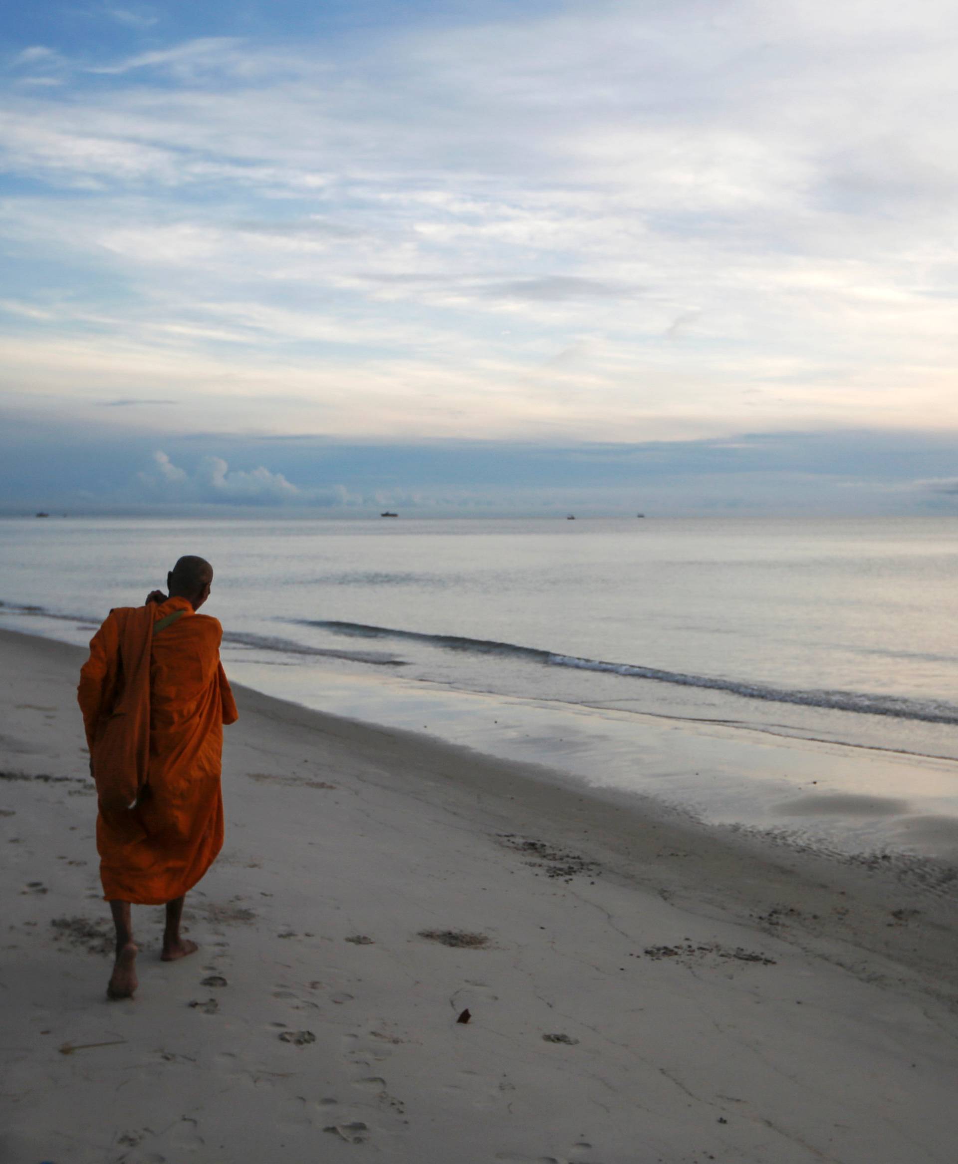 A Buddhist monk walks for alms offerings at a beach in Hua Hin