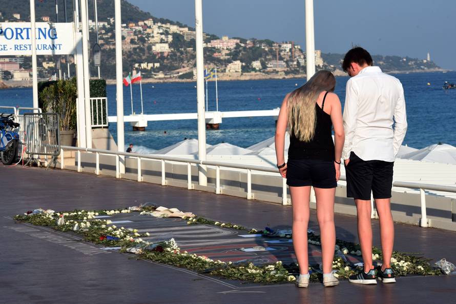 People look at a memorial with flowers, photos and texts to victims on the Promenade des Anglais as part of the commemorations of last year's July 14 Bastille Day fatal truck attack on the Promenade des Anglais in Nice