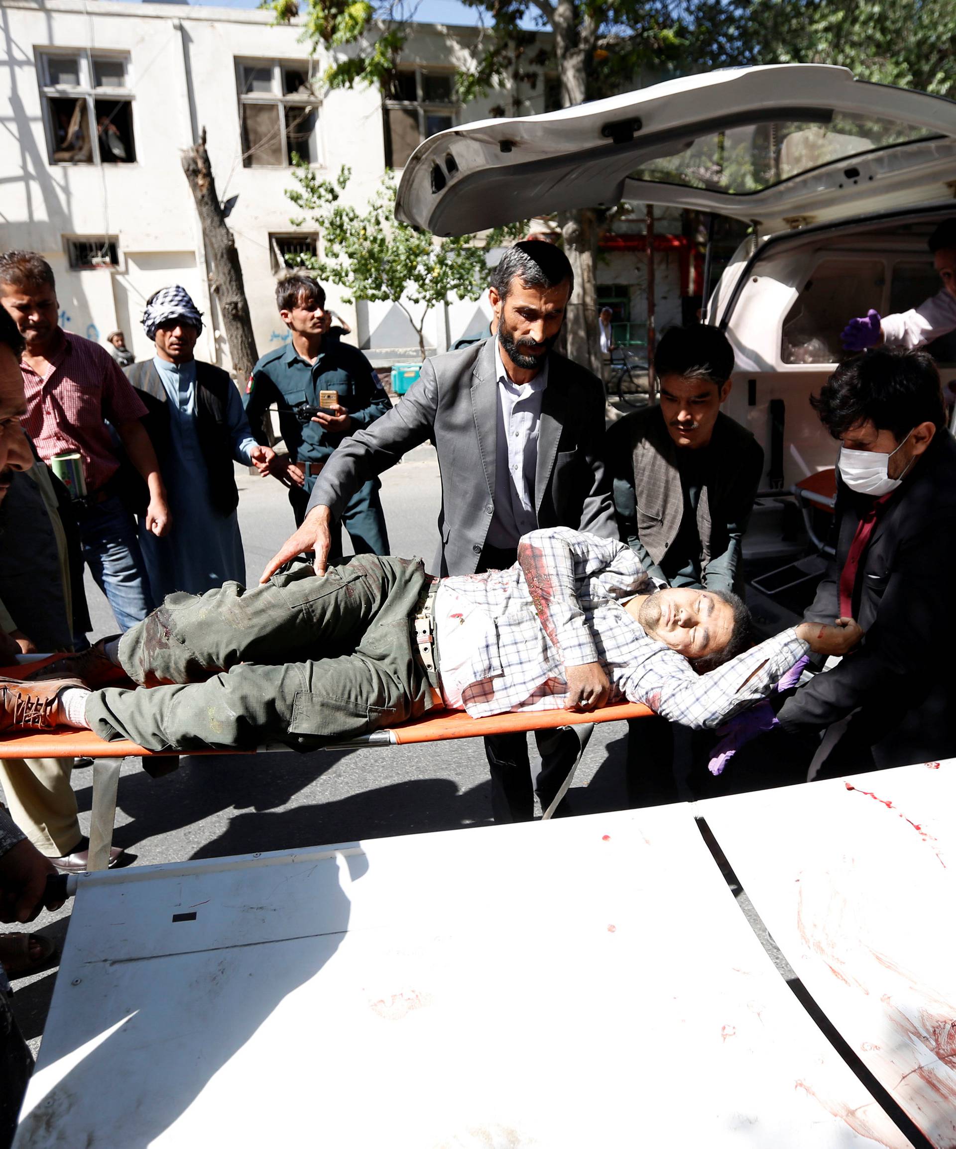Men move an injured man to a hospital after a blast in Kabul, Afghanistan