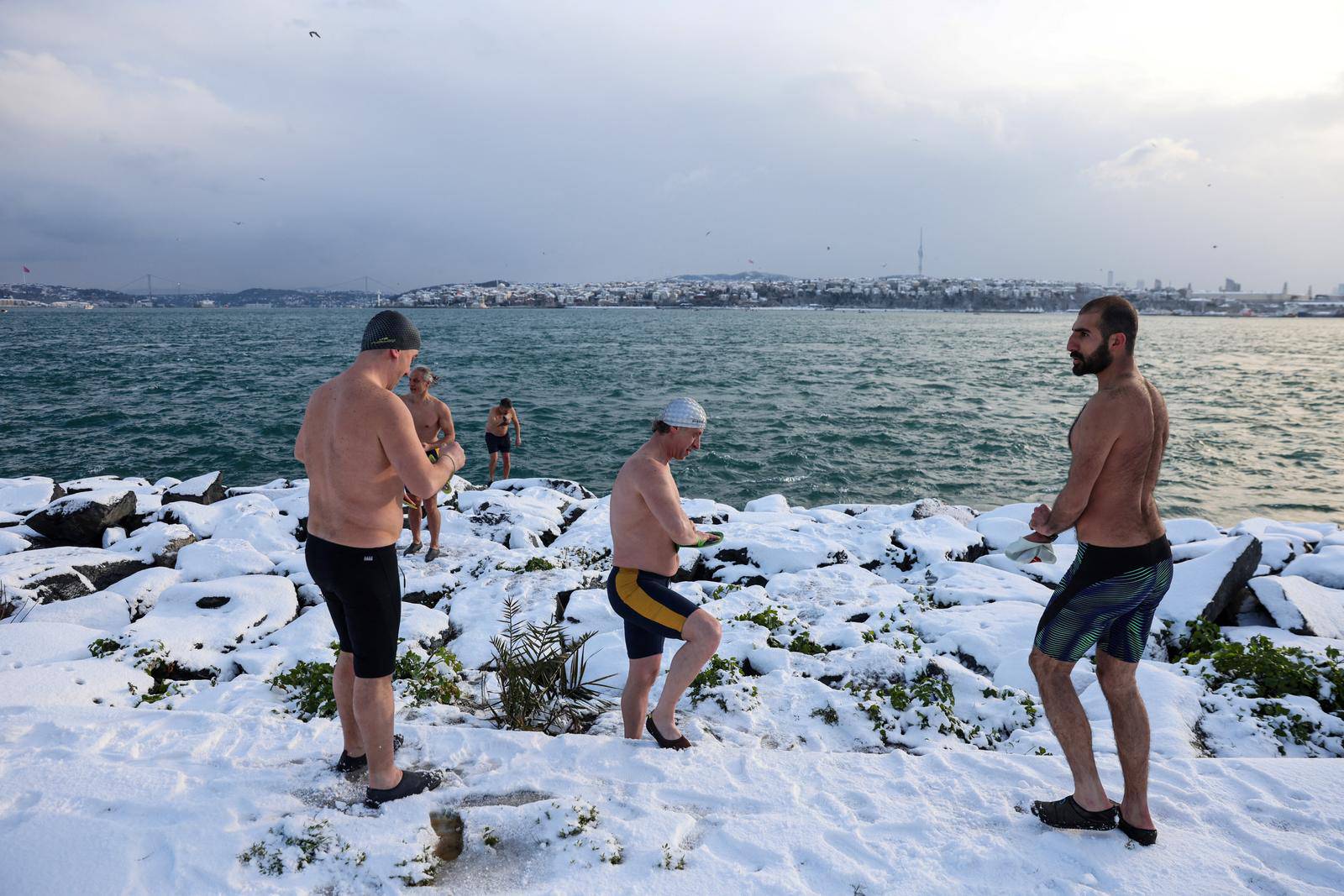 A group of swimmers warm-up before they dive into the chilly waters of the Bosphorus during a snowy day in Istanbul