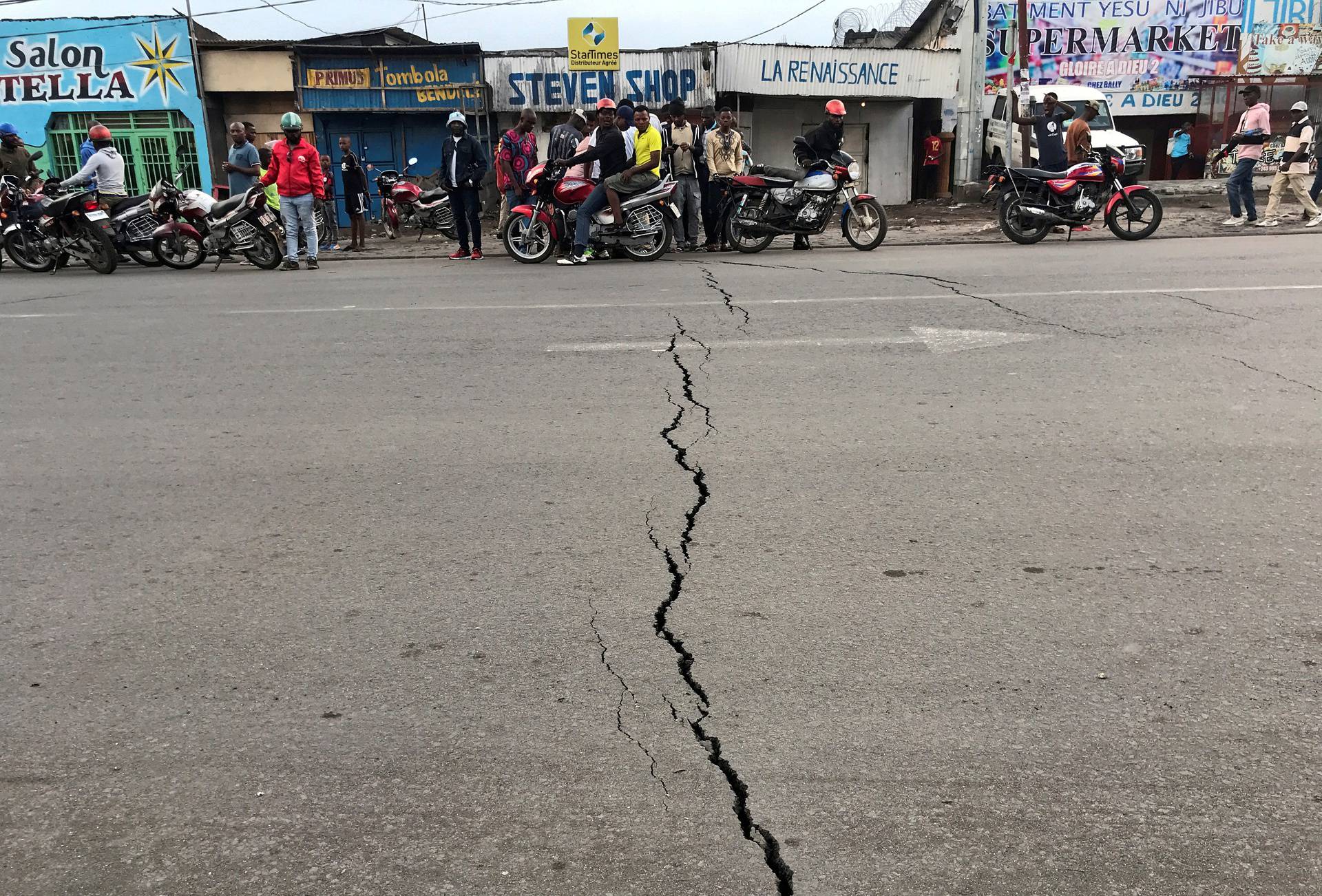 FILE PHOTO: Congolese riders are seen near a crack on the road caused by earth tremors as aftershocks following the eruption of Mount Nyiragongo volcano near Goma