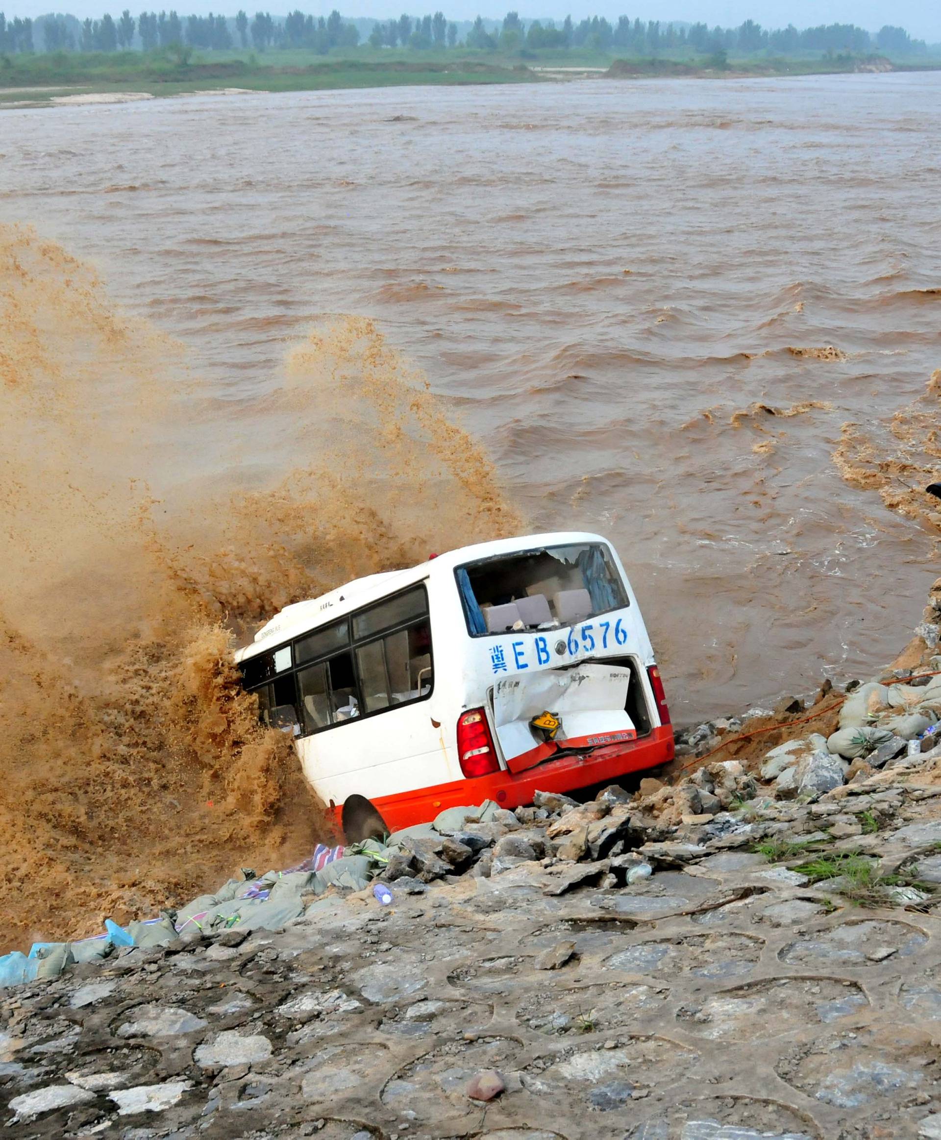 An abandoned bus filled with sand bags is used to build a makeshift dike at a flooded area in Xingtai, Hebei Province