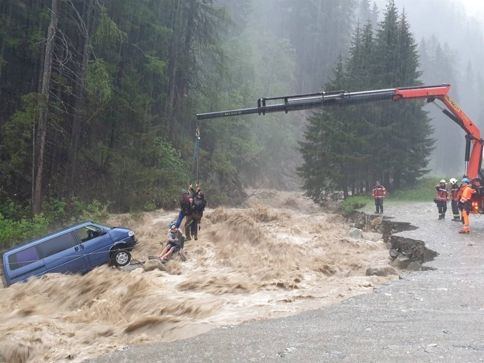 Two occupants of stranded van are lifted unhurt by a crane during heavy rain in Spluegen