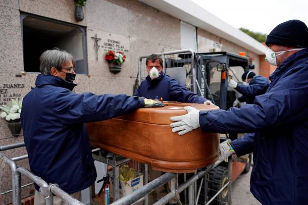 Employees of a mortuary carry the coffin of a person who died from the coronavirus disease (COVID-19) at the Carabanchel cemetery in Madrid
