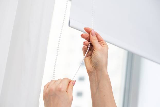 Woman,Opening,White,Roller,Blind,On,Window,Indoors,,Closeup