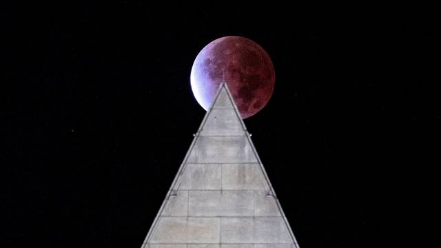 The Beaver 'blood' Moon partial lunar eclipse is seen above the Washington Monument in Washington