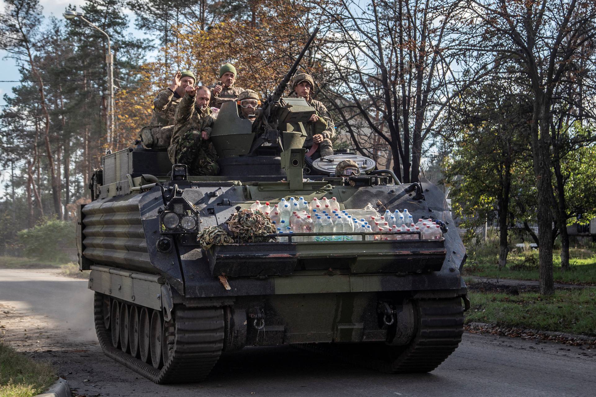 Ukrainian servicemen ride atop of an M113 armoured personnel carrier (APC) in the town of Lyman