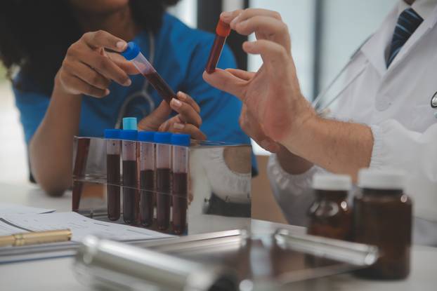 Medical worker in lab coat and sterile mask, doing a microscope 