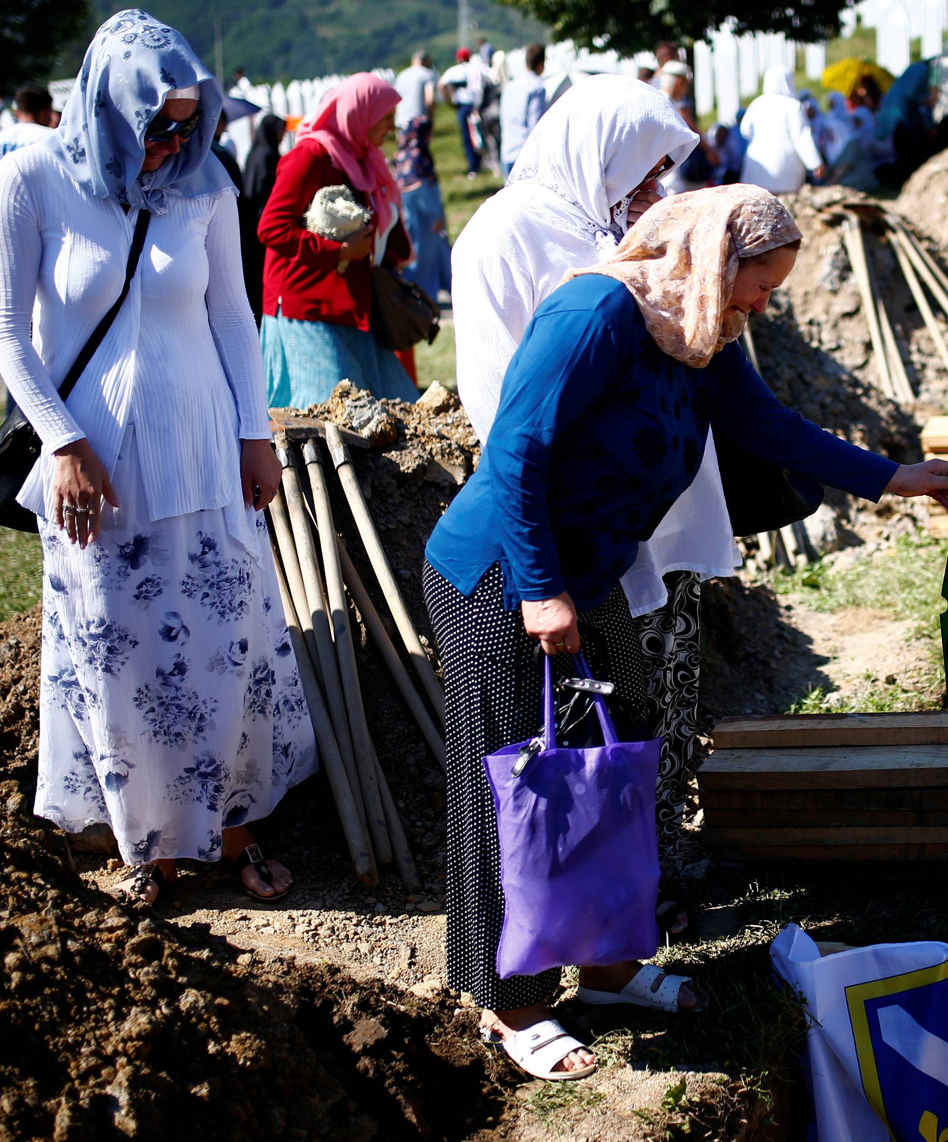 Muslim women cry next to a grave before mass funeral in Memorial Center in Potocari near Srebrenica